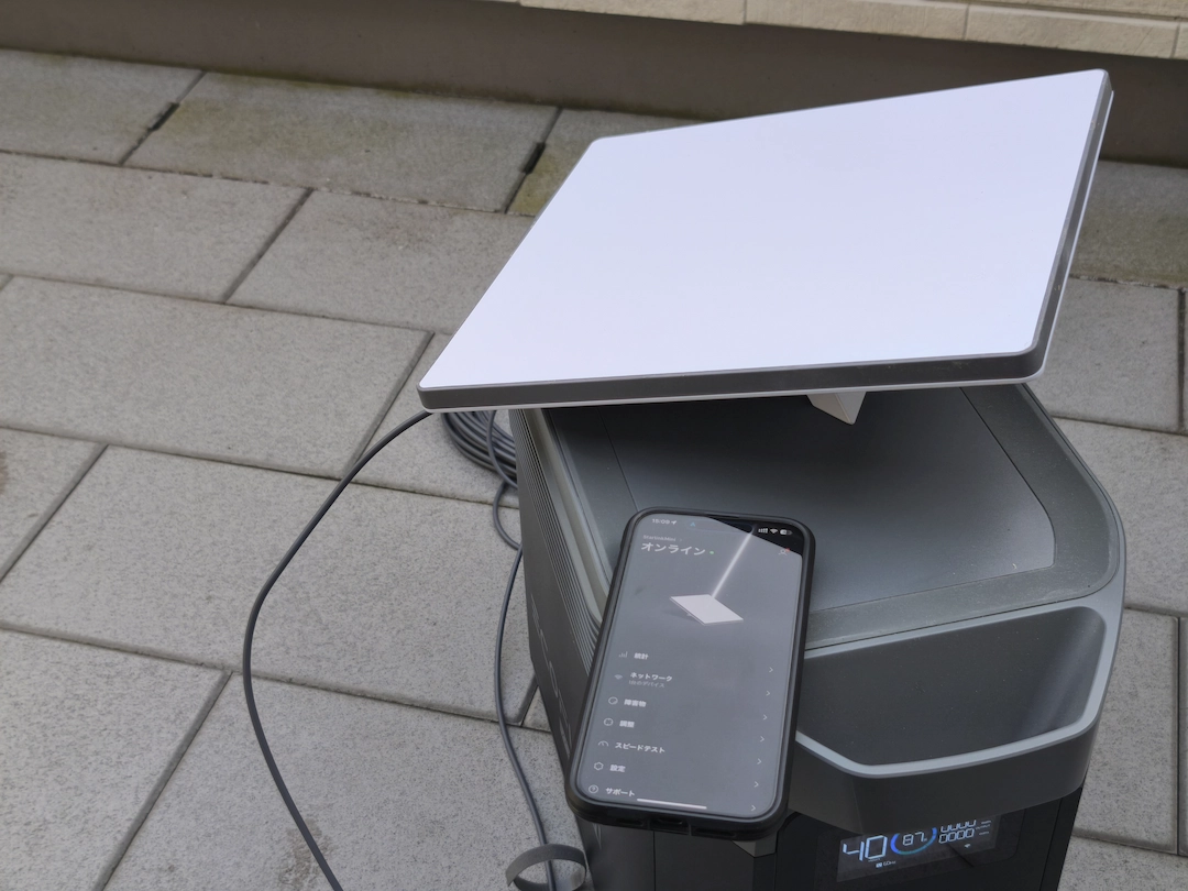 Starlink Miniのセットアップ風景。屋外に設置し、スマートフォンのアプリで接続状態を確認している。