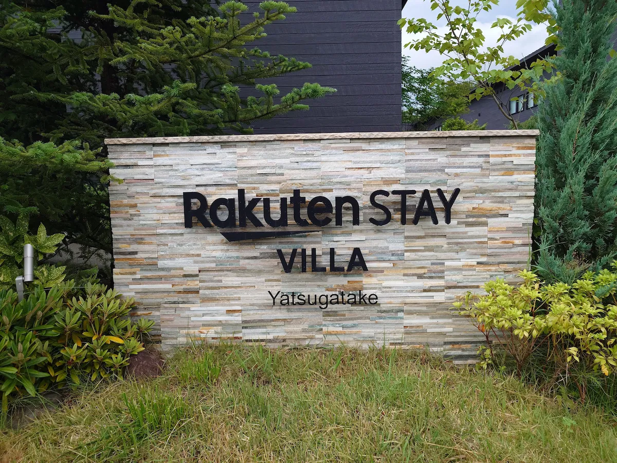 モダンな石垣に設置された「Rakuten STAY VILLA Yatsugatake」のエントランス看板。周囲の緑と調和したデザインになっている。